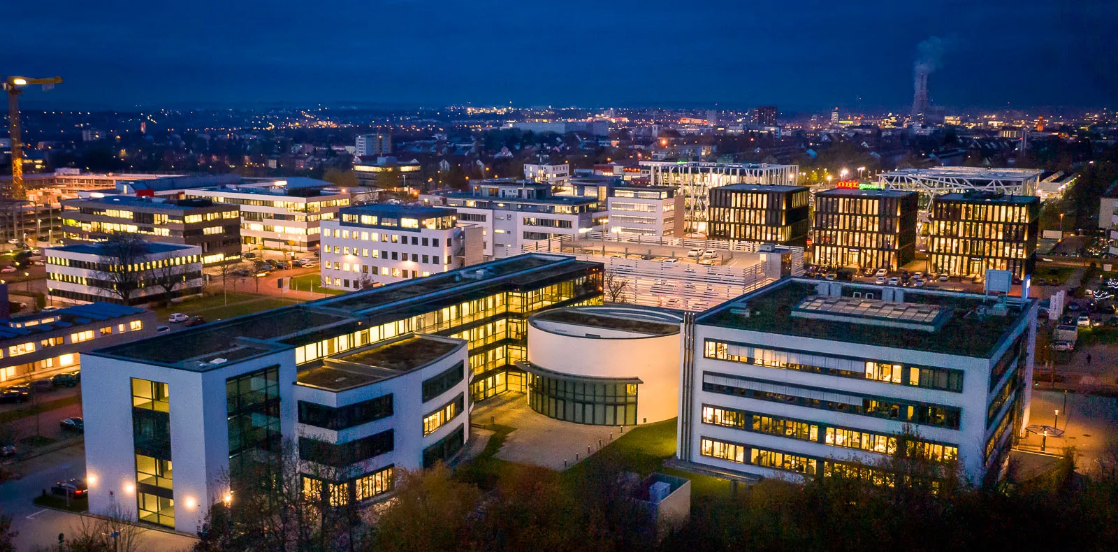 Beleuchtete Büro- und Geschäftsgebäude zur blauen Stunde, Luftaufnahme
